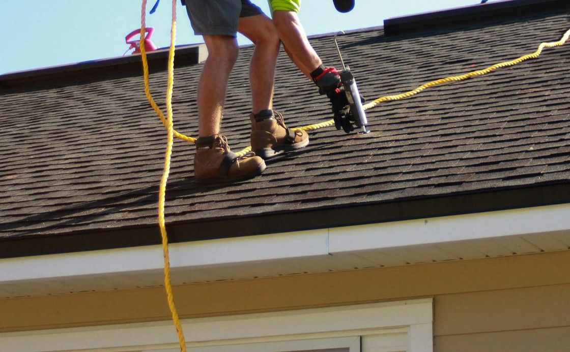 a man working on a roof with a power drill